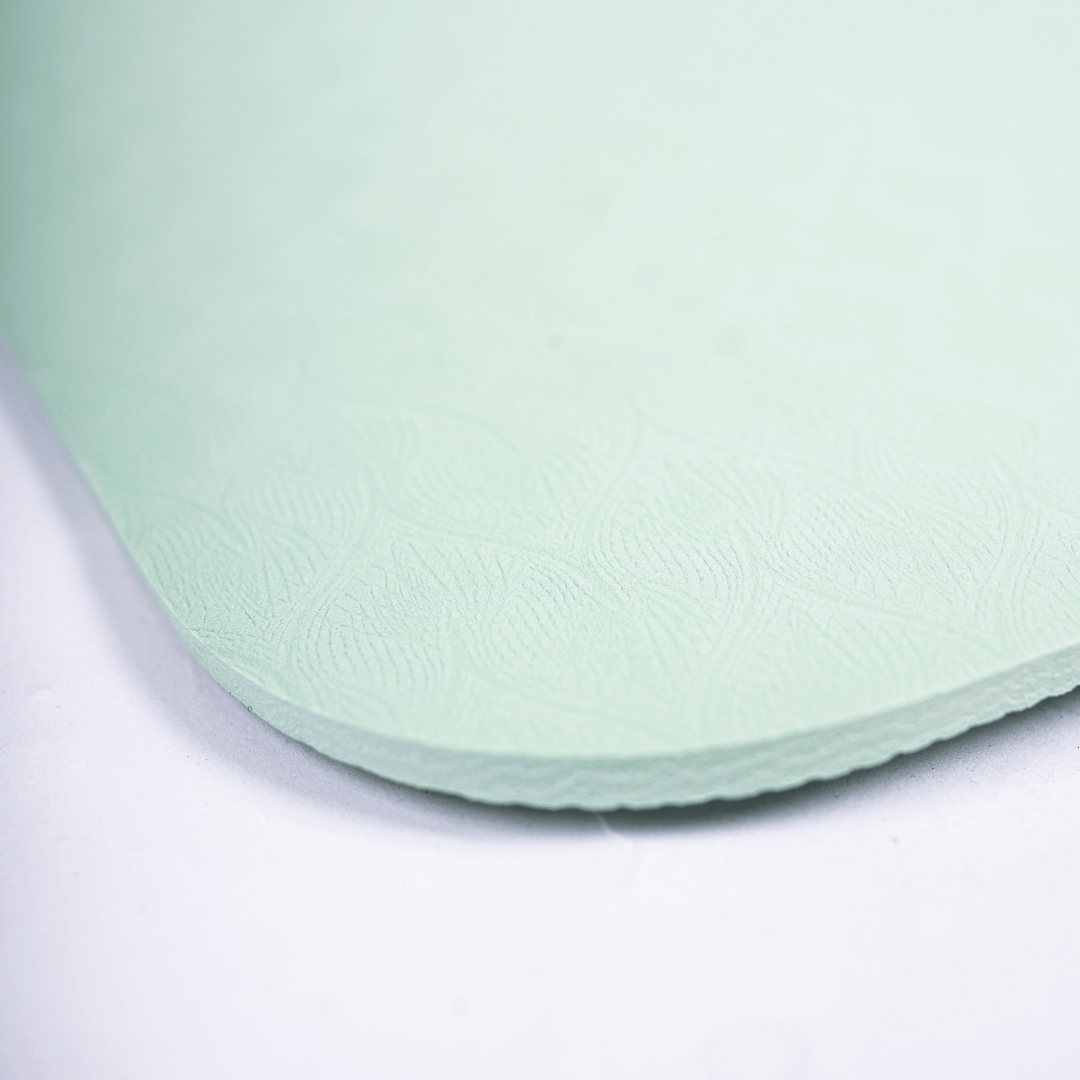 Nærbillede af Smart Makros yogamåtte i støttende og skridsikkert TPE-materiale. Miljøvenlig yogamåtte uden PVC og latex. 0,6 cm tyk måtte med blød struktur og dæmpende effekt. Yogamåtte til ledaflastning ved knæ, hofter og håndled. Komfortabel træningsmåtte til kvinder. Grønt yogaunderlag med blødt mønster og skridsikker overflade – ideel til yoga, pilates, udstrækning og hjemmetræning. Lang og fleksibel måtte til alle højder (183 cm). Yogamåtte med god støddæmpning og stabilitet. Ideel til træning i overga